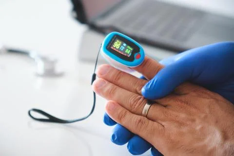 Pulse oximeter measuring oxygen saturation on patient finger Stock Photos