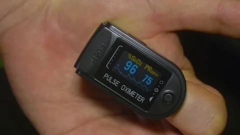 Pulse oximeter O2 saturation at 96% during test on patient index finger Stock Footage 130854022