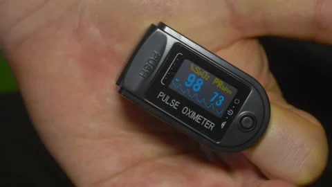 Pulse oximeter O2 saturation at 98% during patient test in index finger Stock Footage 130854377