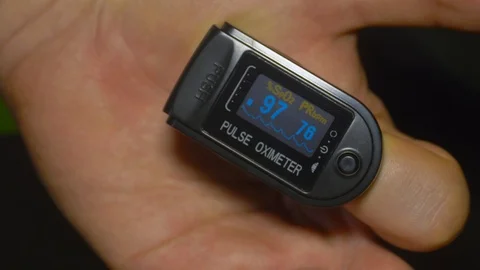 Pulse oximeter testing O2 saturation at 97% on patient index finger Stock Footage 129814632