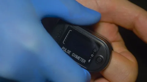 Pulse oximeter testing saturation and heart rate on patient finger Stock Footage 129814515