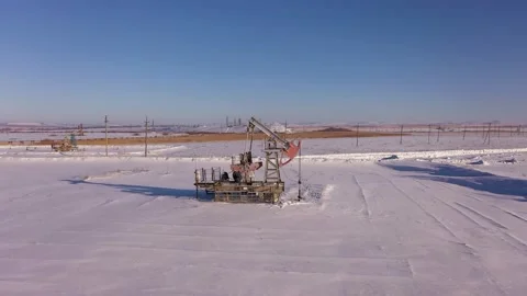 Pump jack in vast oil fields in winter. Pipelines transporting oil from oil Stock Footage 172054193