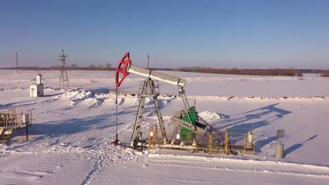 Pump jack in vast oil fields in winter. Pipelines transporting oil from oil Stock Footage 172204626