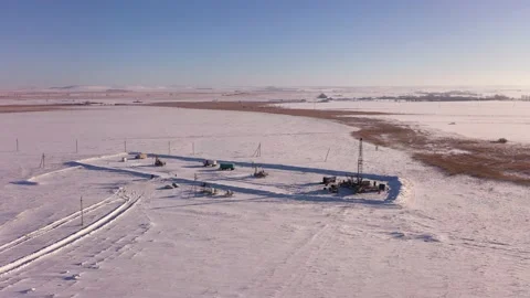 Pump jack in vast oil fields in winter. Pipelines transporting oil from oil Stock Footage 172366688