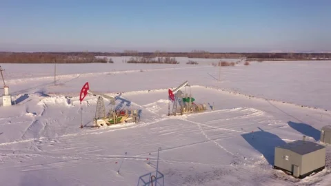 Pump jack in vast oil fields in winter. Pipelines transporting oil from oil Stock Footage 172538089
