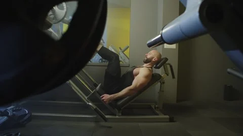 A pumped-up bearded man performs an exercise on the muscles of the legs. Stock Footage 240302877