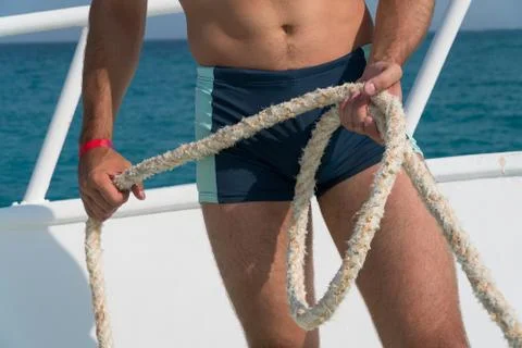 The pumped guy holds the rope on the bow of the yacht Stock Photos