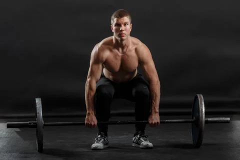 A pumped up man doing sport exercise by lifting gymnastic barbell Stock Photos