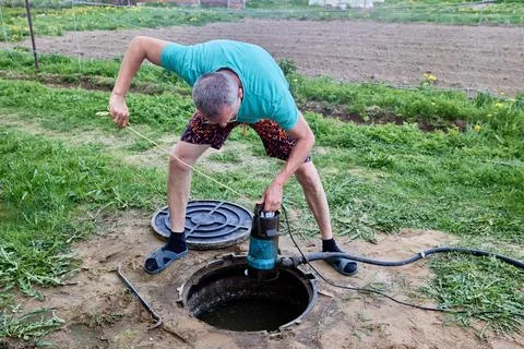 Pumping sewage from septic tank using submersible wastewater pump. Stock Photos