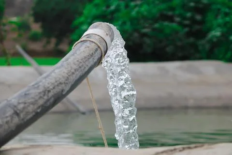 Pumping water out of plastic pipe into the ground,Water from a well filled a  Stock Photos
