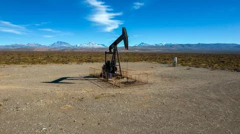 Pumpjack extracting oil with mountainous background Stock Photos