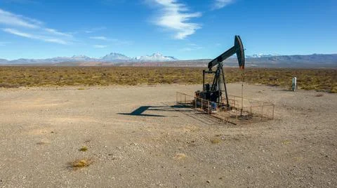 Pumpjack extracting oil with mountainous background Stock Photos