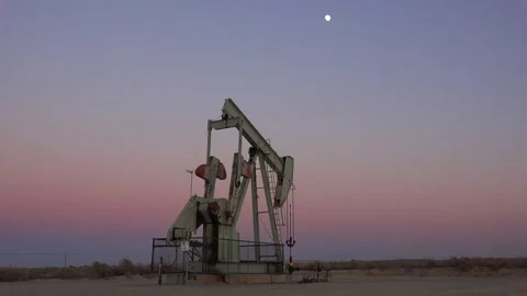 Pumpjack operates at twilight with moon in desert landscape. Stock Footage 337805340