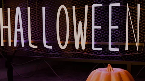 Pumpkin and neon sign emerging through amber haze with drifting embers, 4K Stock Footage 346188574