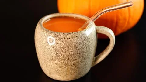 Pumpkin beverage inside ceramic mug, glass straw, pumpkin placed behind, vibrant Stock Photos