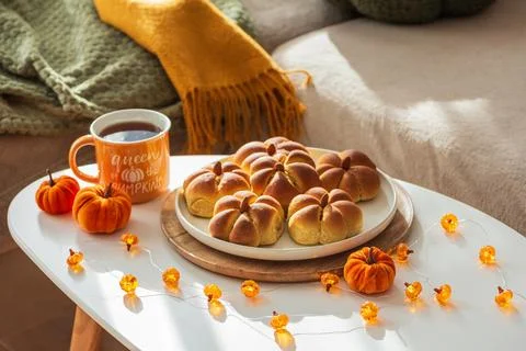 Pumpkin bread rolls, tea and cozy autumn season decor Stock Photos