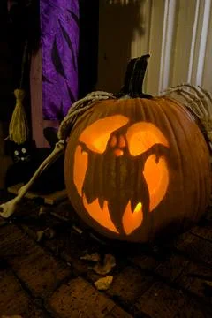 Pumpkin carved with a ghost image glows on front porch Stock Photos