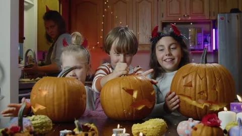 Pumpkin Carving Moment At Kitchen Table During Halloween With Mother And Kids Stock Footage 313542038