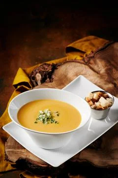 Pumpkin cream soup in white beautiful plate on wooden cut on a metal rusty Stock Photos