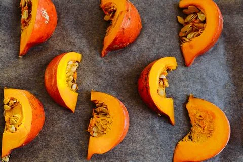 Pumpkin cut into slices on baking sheet Stock Photos