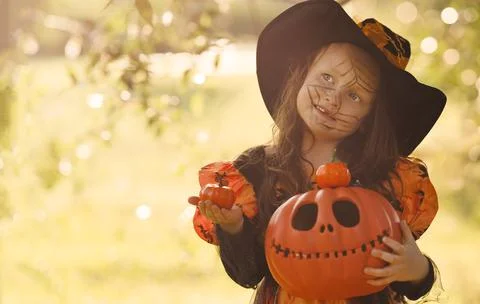 Pumpkin head Jack-o'-lantern in the hands of a girl in a witch costume on Stock Photos
