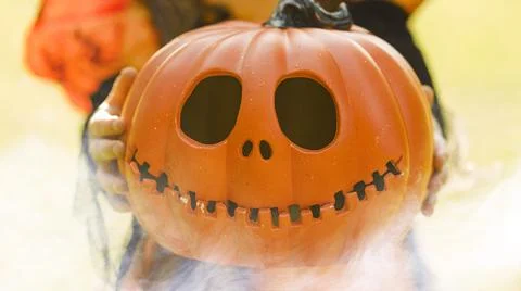 Pumpkin head Jack-o'-lantern in the hands of a girl in a witch costume , close Stock Photos