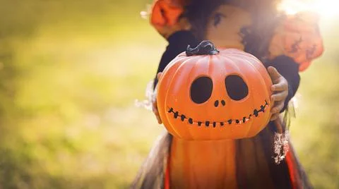 Pumpkin head Jack-o'-lantern in the hands of a girl in a witch costume , close Stock Photos
