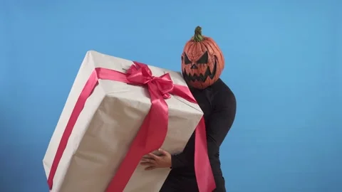 Pumpkin headed man on a blue background with a large gift Stock Footage 141603932