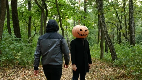 A pumpkin-headed man gets in the woods. He pulls out a knife and run Video stock 116497737