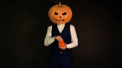 Pumpkin-headed man takes something from a halloween pumpkin. Halloween concept. Stock Footage 116225256