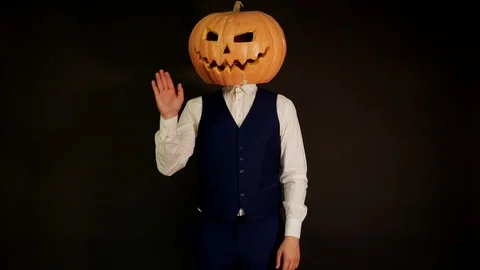 Pumpkin-headed man waves his hand. Halloween concept.carved pumpkin. Stock Footage 116231743