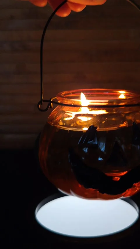 A pumpkin holding a lantern with a burning candle in the dark, macro photography Stock Footage 319789353
