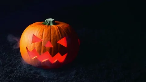 A pumpkin with its face cut out releases heavy smoke onto black ground. Hallo Stock Footage 214805519