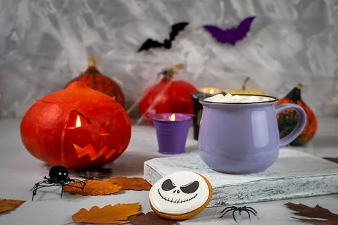 Pumpkin jack-o-lantern and hot cocoa on a spooky Halloween-themed table Stock Photos