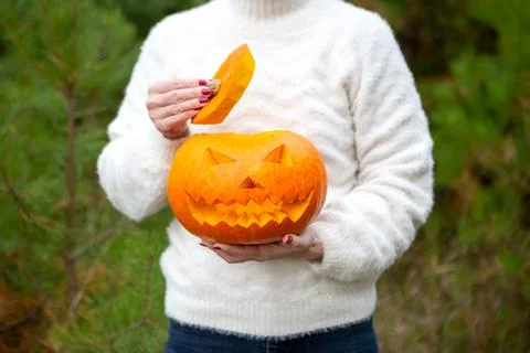 Pumpkin jack-o-lantern in the hands of a girl. close-up. Halloween party Stock Photos