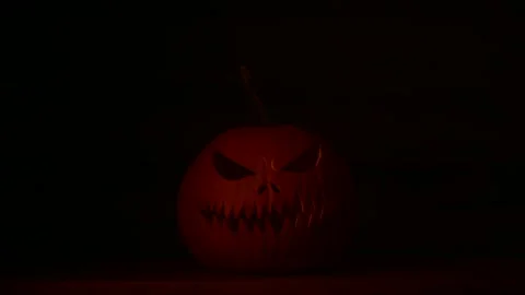 Pumpkin lantern glows with pulsing light in dark Halloween scene Stock Footage 313630366