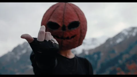 Pumpkin Mask Worn by a Person Gesturing in the Snowy Mountains for Halloween 库存影片 331110413
