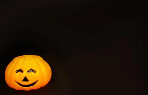 Pumpkin orange, plastic with a smiling face on a black background Stock Photos