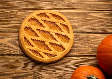 Pumpkin pie on rustic wooden background with whole pumpkins. Traditional Amer Stock Photos