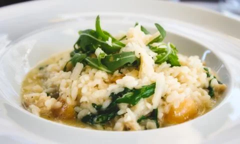 Pumpkin risotto with rocket leaves and parmesan cheese shavings in white dish Stock Photos
