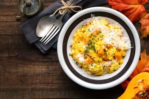 Pumpkin risotto with thyme and parmesan cheese against dark wooden background Stock Photos