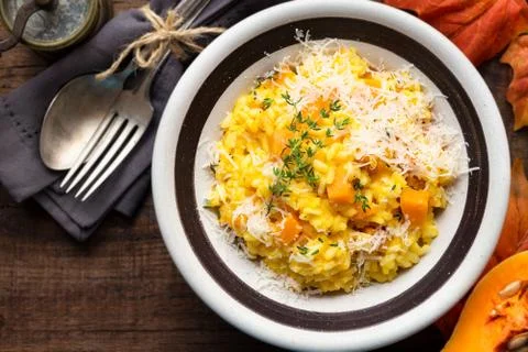 Pumpkin risotto with thyme and parmesan cheese against dark wooden background Stock Photos