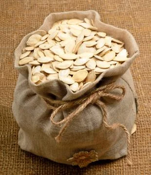 Pumpkin seeds in the bag on the sacking background Stock Photos