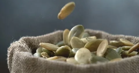 Pumpkin seeds falling into burlap sack in super slow motion Stock Footage 344849936