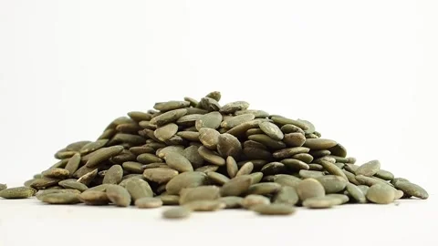Pumpkin seeds stacked on a white surface in a close view Stock Footage 337982452