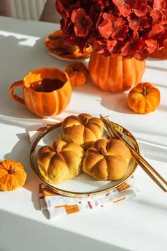 Pumpkin-shaped bread rolls with autumn decoration and hot drink Stock Photos