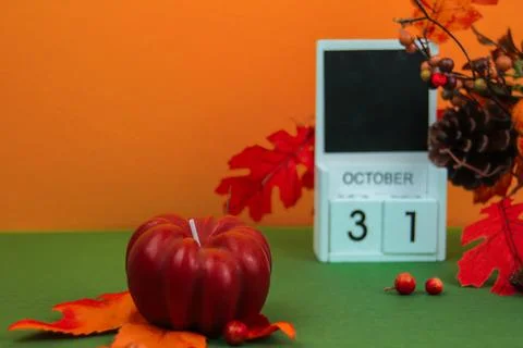 A pumpkin-shaped candle stands Stock Photos