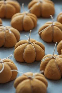 Pumpkin shaped dinner rolls on baking paper Stock Photos