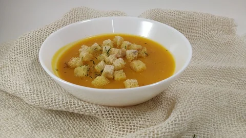 Pumpkin soup and dill falling into white plate Stock Footage 104547181