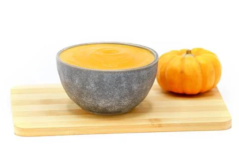 Pumpkin soup in a bowl isolated on white background and a wooden spoon. Stock Photos